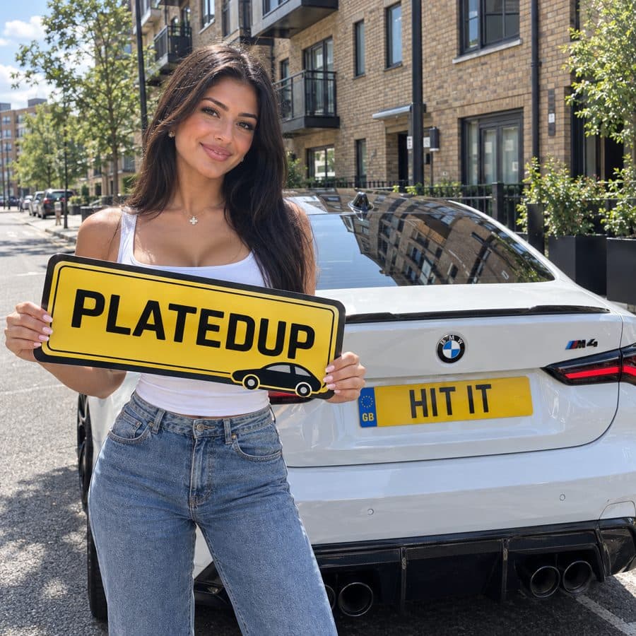 Woman holding a PlatedUp sign beside a white BMW M4 with a show plate