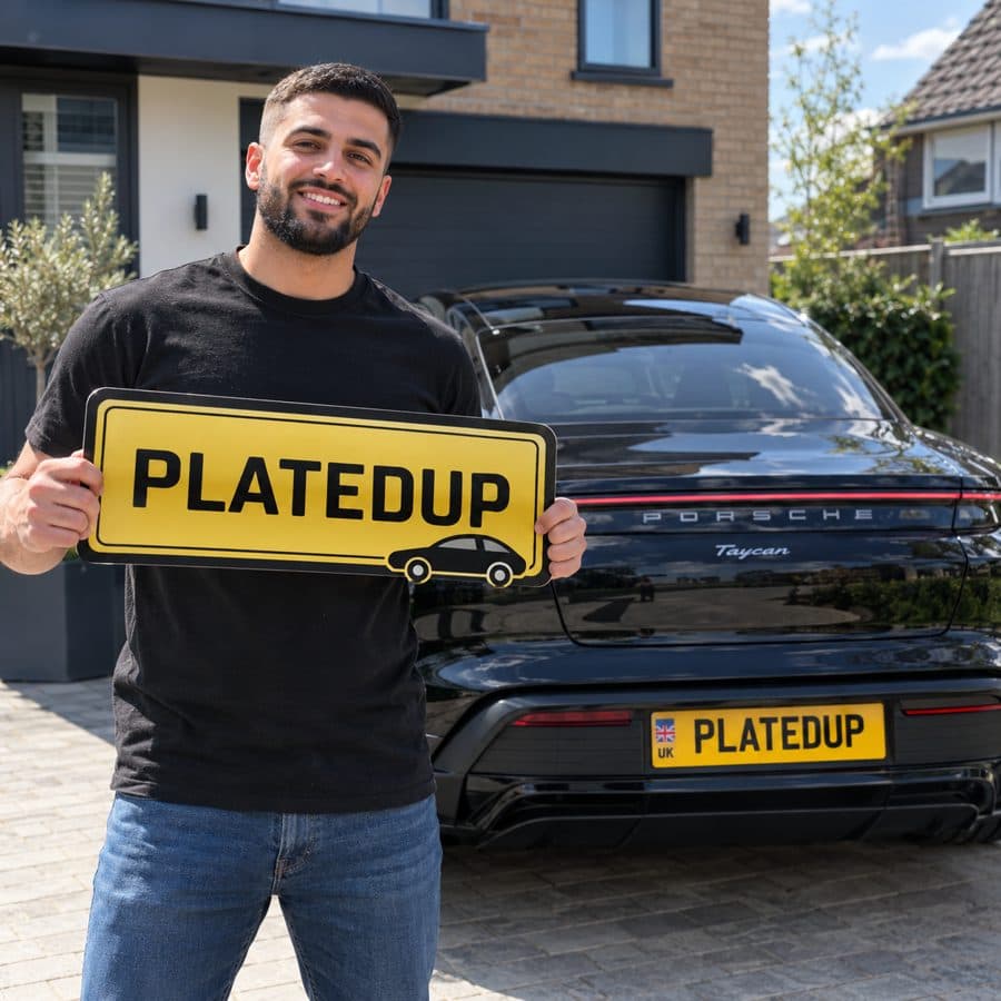 Man holding a PlatedUp sign in front of a black Porsche Taycan with a UK flag number plate